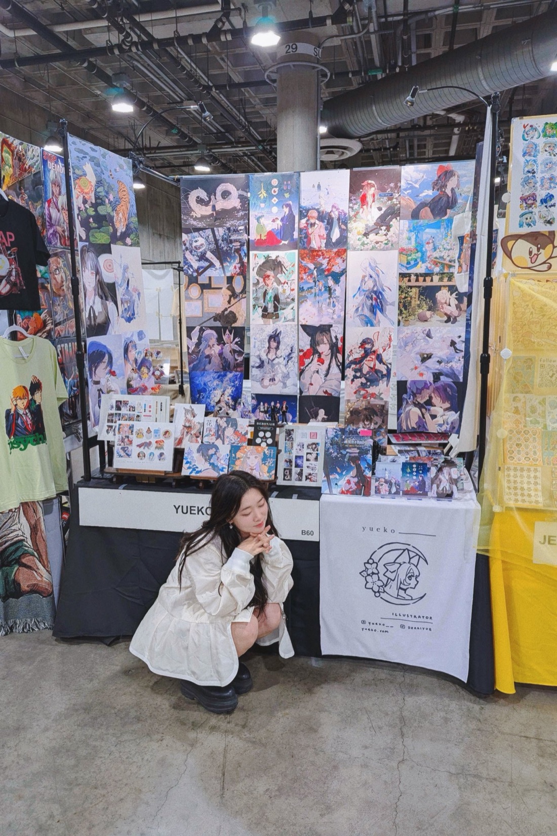 yueko at her artist alley booth, surrounded by her prints